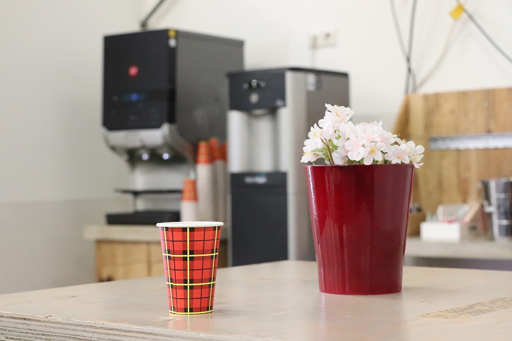 Koffiecorner bij Vindingrijk, met op de voorgrond een koffiebeker en een plant