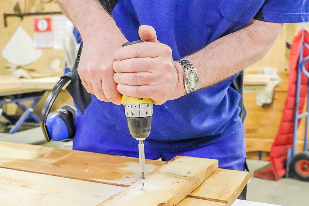 Foto van een medewerker in onze meubelwerkplaats die boort.