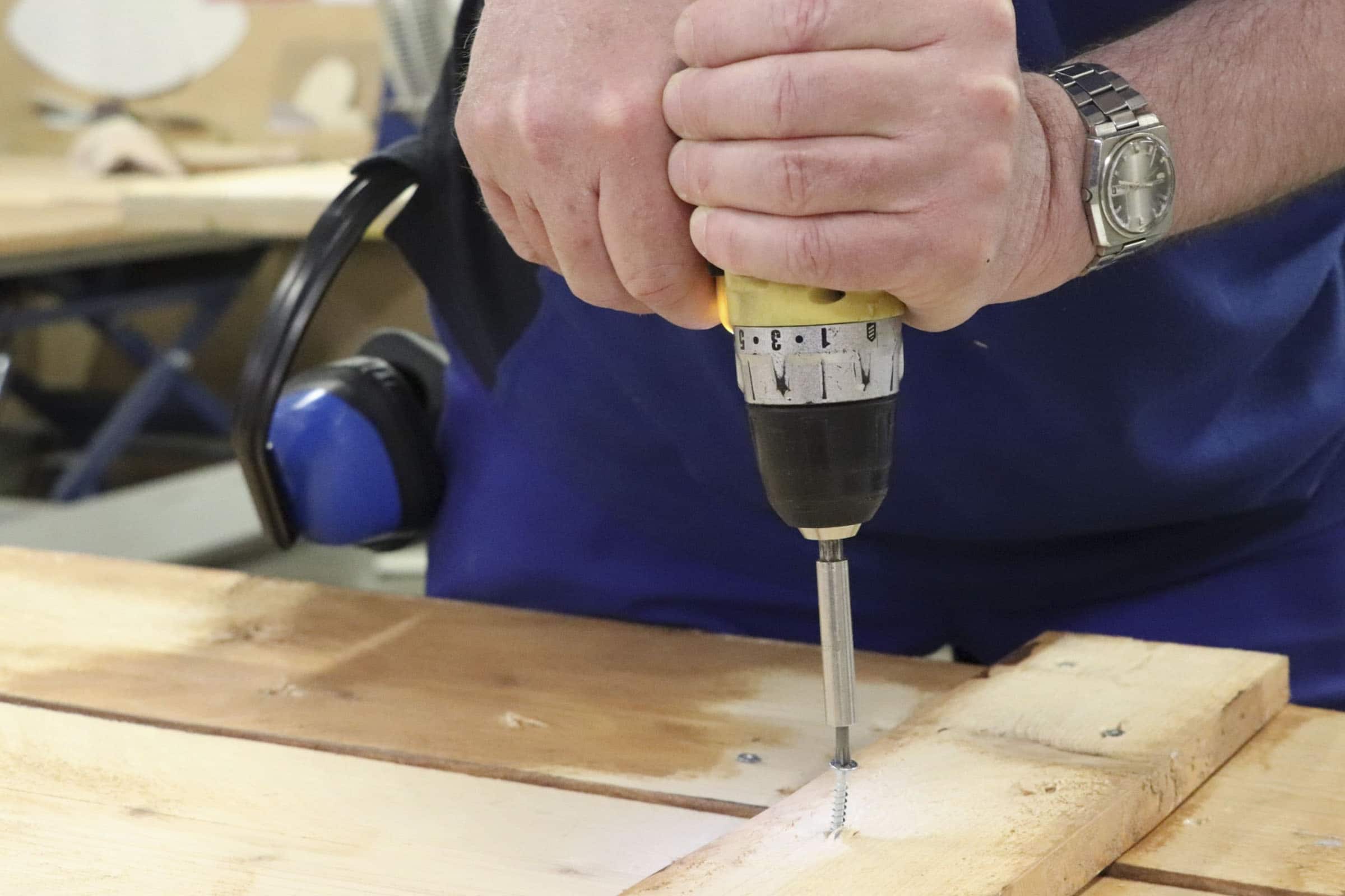 Op de foto boort een medewerker een schroef in hout.