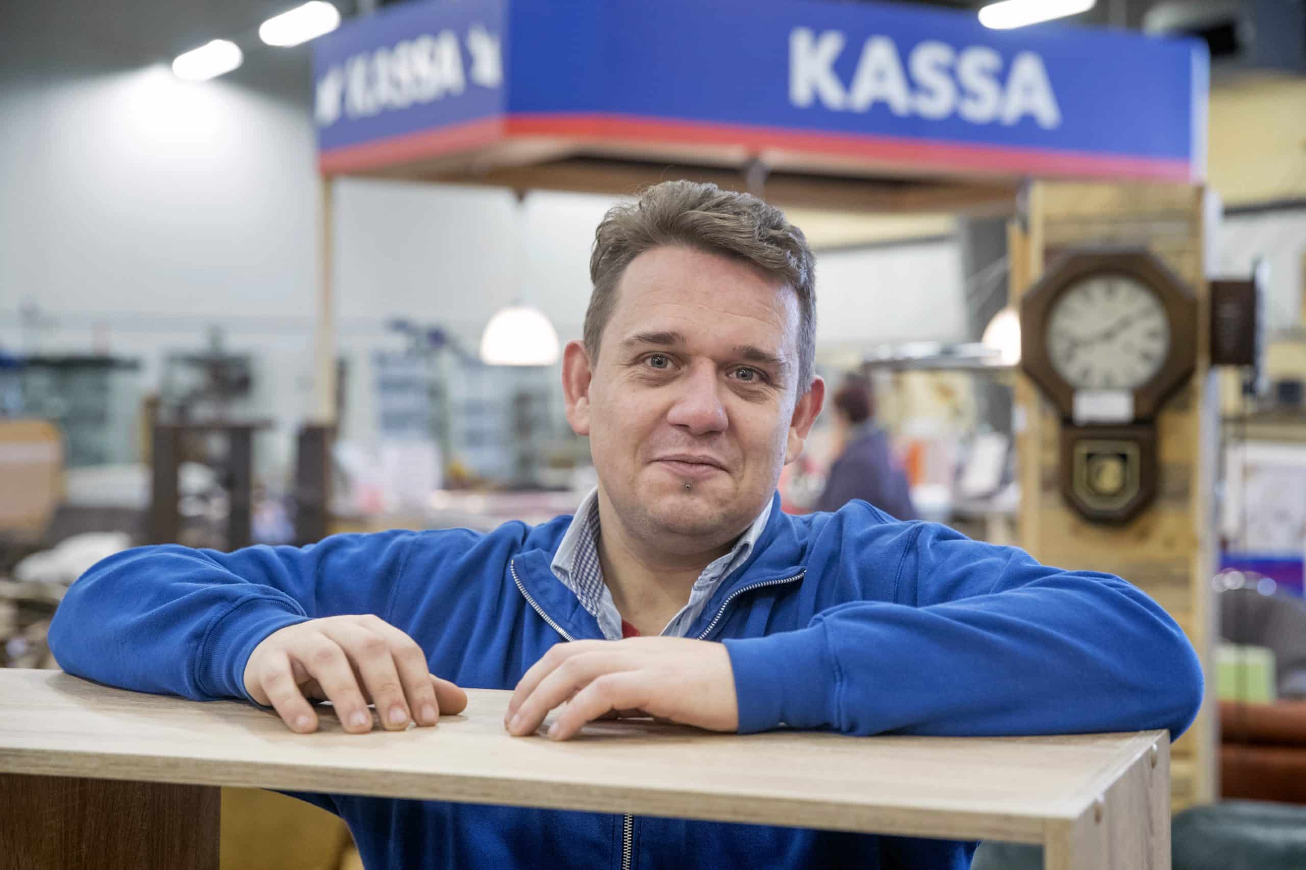 Oude foto van medewerker Theo die leunt op een kast voor de kassa